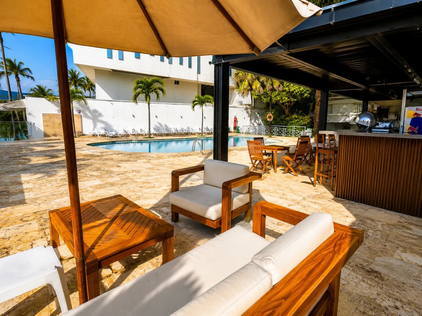 Zona de lounge y bar junto a la piscina, con sillones de teca y vista al mar